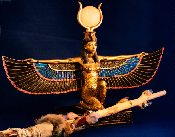 Egyptian goddess Isis kneeling with traditional magic wand made with quartz, amethyst crystals, wood and feathers Egyptian goddess Isis kneeling with traditional magic wand made with quartz, amethyst crystals, wood and feathers on dark midnight blue background horus photos stock pictures, royalty-free photos & images