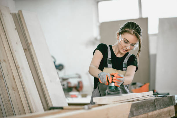 istock Adolescent Female Carpenter Sanding Wooden Block In Home Workshop 1040148010