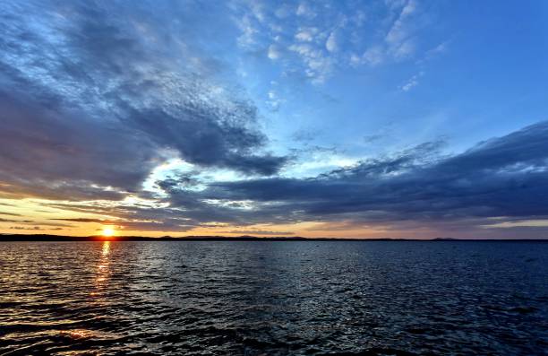 istock dark blue evening sky over the lake, orange sun 1040148204