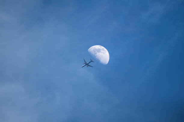 istock plane passing through the Moon from bottom view with long condensation tail on blue sky 1040157704