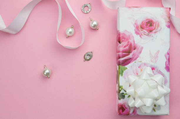 istock Gift wrapped box with ribbon and charms on pink background with space for text 1040179530