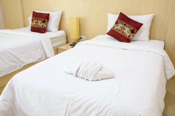 спальня отеля и простыня, концепция интерьера: белое полотенце для душа на кровати с толстым одеялом и подушками. кровати-близнецы готовы с� - sheet single bed bed duvet стоковые фото и изображения