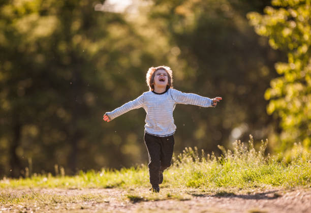 istock Playful little boy screaming while running in the park with arms outstretched. 1040205486
