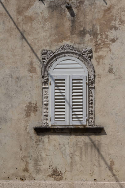 istock Old ornate window crossed by a shadow 1040212824
