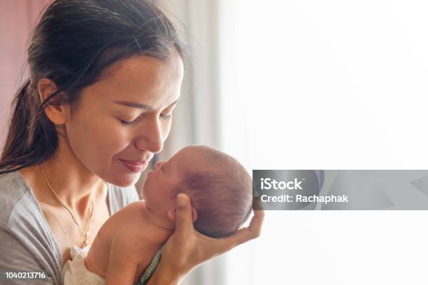 Beautiful Mother Kissing Here Little Cute Baby On Her Palm Mother Take Care Her Little Girl At Home One Week Newborn Girl Stock Photo - Download Image Now