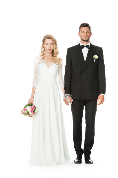 istock attractive young bride and groom holding hands and looking at camera isolated on white 1040289120