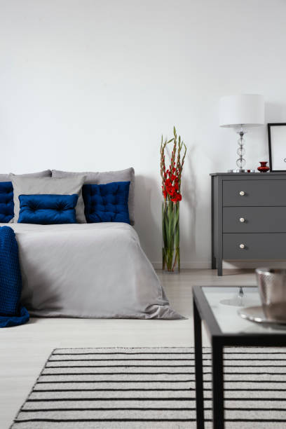 istock A bed dressed in gray bedding and dark blue cushions in a modern bedroom interior. Copy space background. Real photo. 1040300174