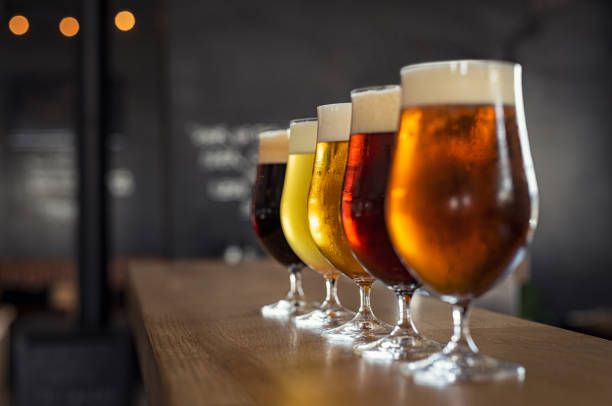 Draught beer in glasses Glasses with different sorts of craft beer on wooden bar. Tap beer in pint glasses arranged in a row. Closeup of five glasses of different types of draught beer in a pub. beer alcohol stock pictures, royalty-free photos & images