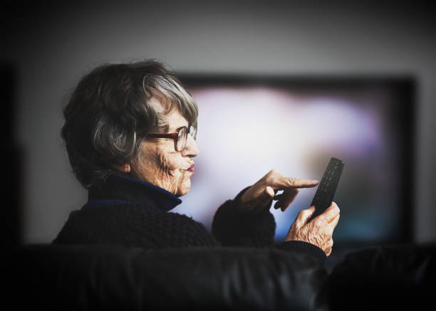 istock Frustrated old woman attempting to use TV remote 1040303594