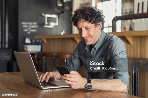 Mature Businessman Working At Cafe Stock Photo - Download Image Now - Men, Laptop, Mobile Phone