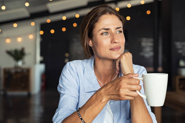 rijpe vrouw koffie drinken - woman thinking stockfoto's en -beelden