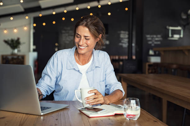 中年の女性のラップトップで仕事する - laptop cafe coffee coffee shop ストックフォトと画像