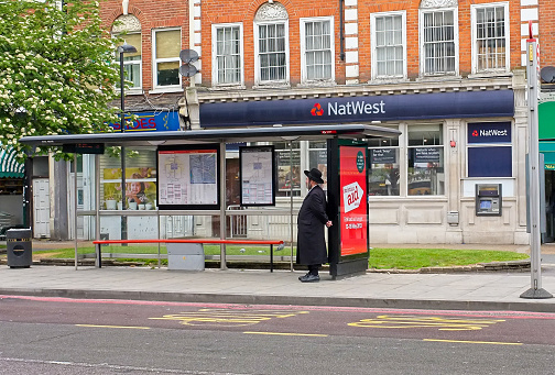 May 19, 2013: A solitary male Hasidic Jew stands at a bus stop on the Amhurst Park road in Stamford Hill, London, UK.