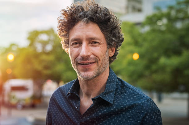 Mature handsome business man Portrait of happy mature man looking at camera outdoor. Senior businessman with beard feeling confident at sunset. Closeup face of business man smiling with city in background. top honor stock pictures, royalty-free photos & images