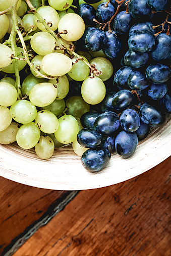 Fresh organic grapes in wooden bowl on rustic wooden table