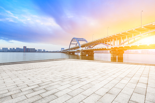 Empty square floor and city skyline with bridge at sunset