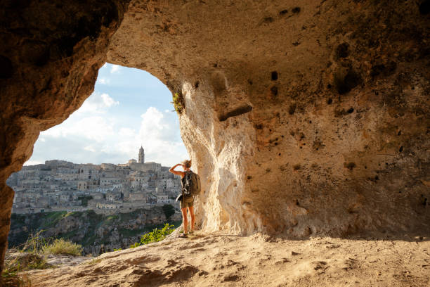 mujer busca en vista de una cueva de matera, basilicata, italy - mochilero fotografías e imágenes de stock