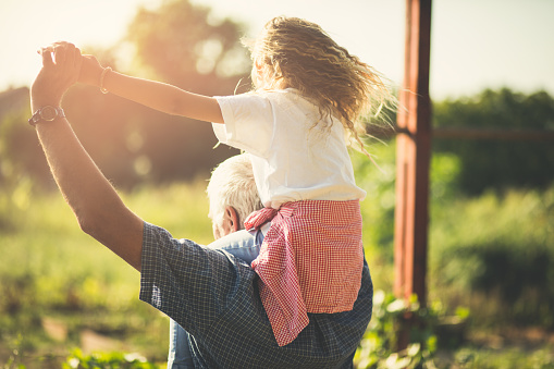 Spend your retirement days with your granddaughter. Grandfather and granddaughter spending time together in nature. Carrying on shoulders. Copy space.