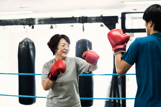 Senior adult women training with male instructor at boxing gym Japanese senior adult women training with male instructor at boxing gym old man boxing stock pictures, royalty-free photos & images