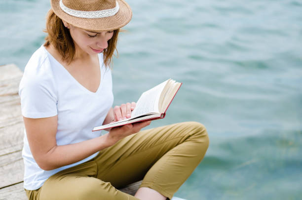 istock Young girl reading a book by the lake 1040334312