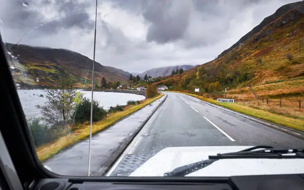 A view out of a landrover defender on the road to Eilean donan castle. It's early in the morning, it's cloudy and is raining.