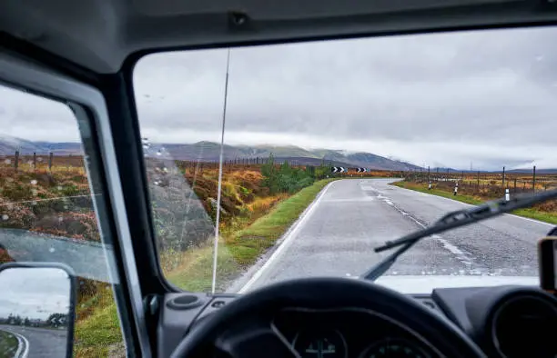 A view out of a landrover defender on the road in the cairngorms. It's early in the morning and it's cloudy.
