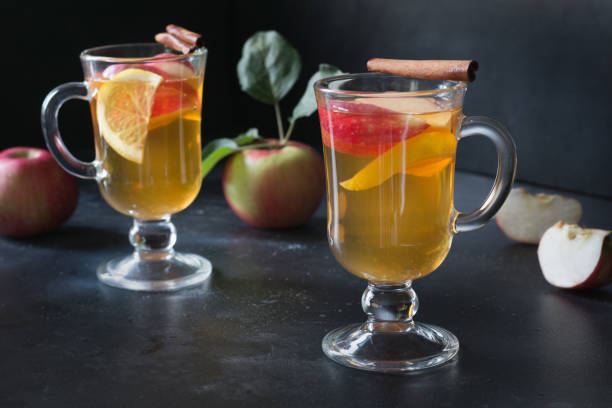 Apple tea with lemon, spiced and cinnamon on black board. Close up. Autumn still life.