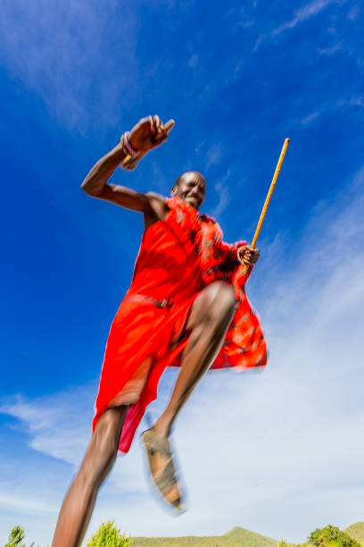 Masai Mara, Kenya - February 10, 2015 - An unidentified African Masai men are dancing at Masai village with tourists and tourist photographers photographing, very close the Masai mara national reserve at Oloolaimutia gate on February 23, 2014 in Masai Mara, Kenya. The Masai people are a Nilotic ethnic group of semi-nomadic people located in Kenya and Tanzania.