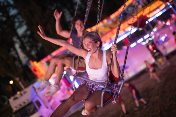 счастливая молодая пара на карусели в парке развлечений - carnival amusement park swing traditional festival стоковые фото и изображения