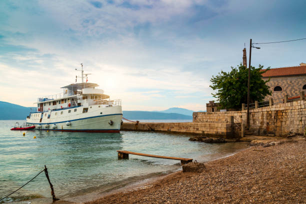 Europe. Mediterranean area. Adriatic sea. Croatia. Dalmatian seascape. Ferry-catamaran floating against the backdrop of a seaside town Kaprije drowning in greenery. Sea transport floating near island.