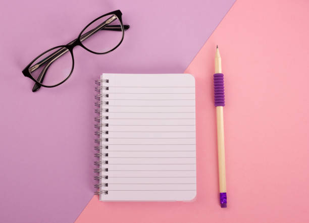 istock Spiral notepad, pencil and glasses on pastel background. 1040371678