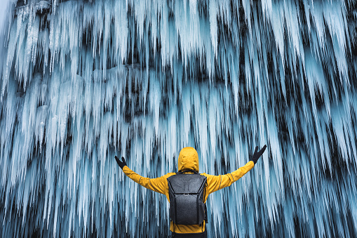 Man in yellow jacket watching a spectacular frozen waterfall (Pericnik, Slovenia).