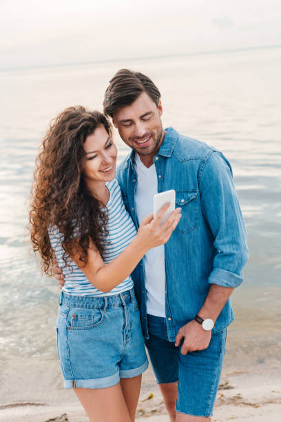 istock young smiling couple using smartphone near sea 1040385496
