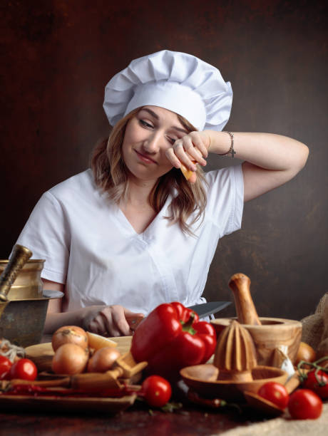 istock Young beautiful girl in a chef uniform cuts onions. 1040400678