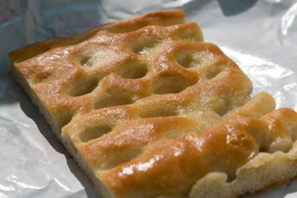 primo piano di una fetta di focaccia su carta bianca, un pane oleoso tipico della regione liguria. - pizza bianca foto e immagini stock