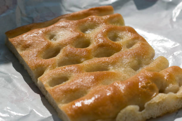 Close-up of a slice of focaccia on white paper, an italian oily bread typical of liguria region. stock photo