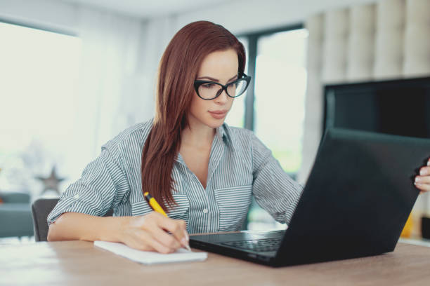 istock Young diligent woman writing notes at laptop 1040404258
