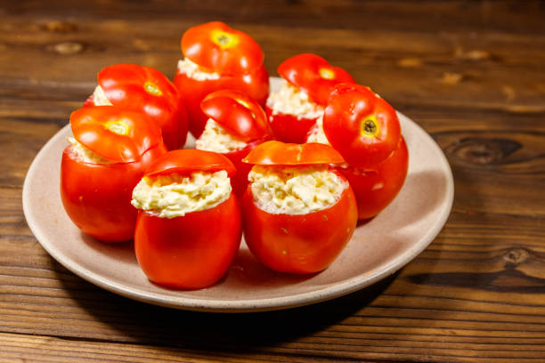tomates rellenos con queso en mesa de madera - stuffed tomato fotografías e imágenes de stock