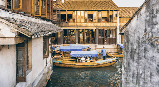 Suzhou, China - Nov 5, 2016: Several tourist boats with passengers onboard maneuver a narrow part of the waterway at the historic Zhouzhuang Water Town.