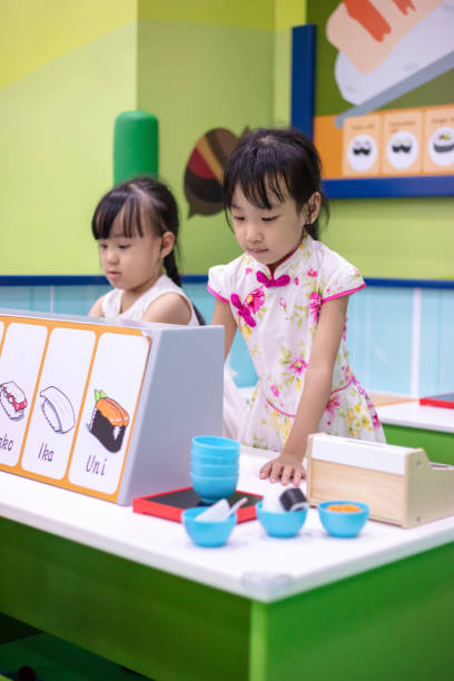 Asian Chinese little sisters role-playing at sushi store Asian Chinese little sisters role-playing at sushi store at indoor playground Franchise In Malaysia stock pictures, royalty-free photos & images
