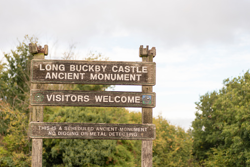 Old wooden public footpath sign post with long buckby ancient castle welcomes visitors in England.