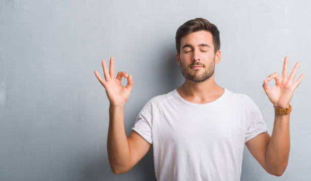 istock Handsome young man over grey grunge wall relax and smiling with eyes closed doing meditation gesture with fingers. Yoga concept. 1040432914