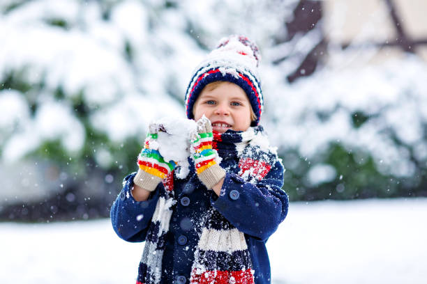istock Funny little kid boy in colorful clothes playing outdoors during strong snowfall 1040443990