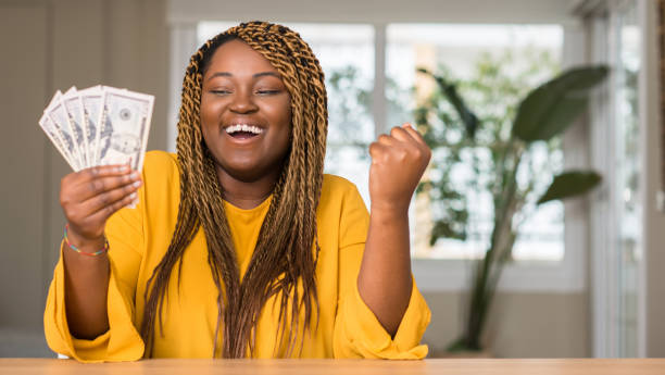 afro-americana mulher segurando dólares gritando orgulhoso e comemorando a vitória e sucesso muito animado, aplaudindo a emoção - holding money - fotografias e filmes do acervo