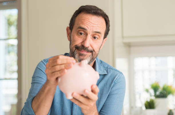 istock Middle age man save money on piggy bank with a confident expression on smart face thinking serious 1040455216