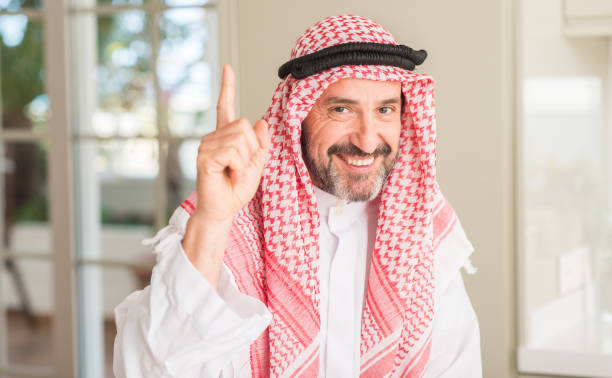 istock Middle age arabian man at home surprised with an idea or question pointing finger with happy face, number one 1040456042