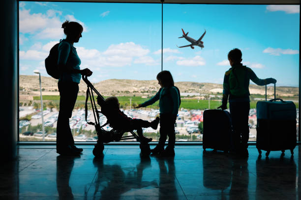 мать с детьми и багажом глядя на самолеты в аэропорту - travel baby people traveling family стоковые фото и изображения