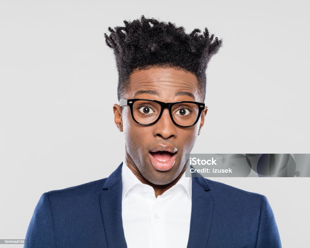 Afro american man in suit looking surprised Close up of afro american man in suit looking surprised. African businessman wearing nerd glasses with mouth open on white background. Adult Stock Photo