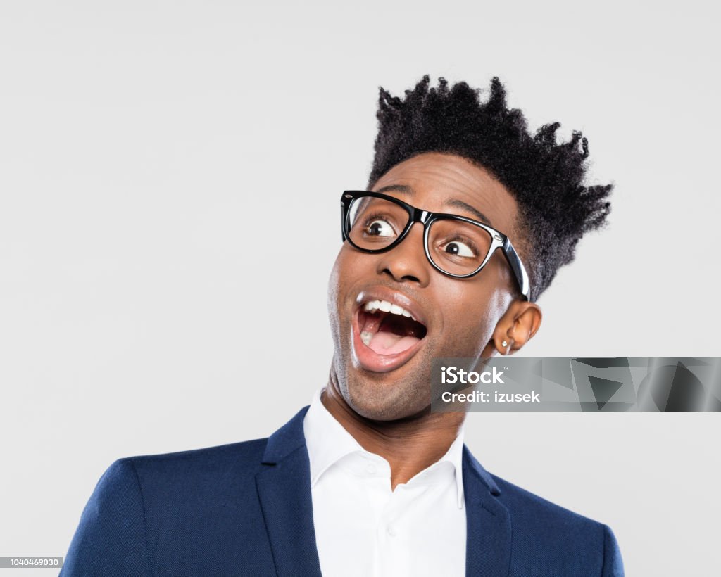 Surprised afro american young businessman Studio portrait of surprised afro american young man in business suit and nerd glasses looking up with mouth open on white background. Awe Stock Photo