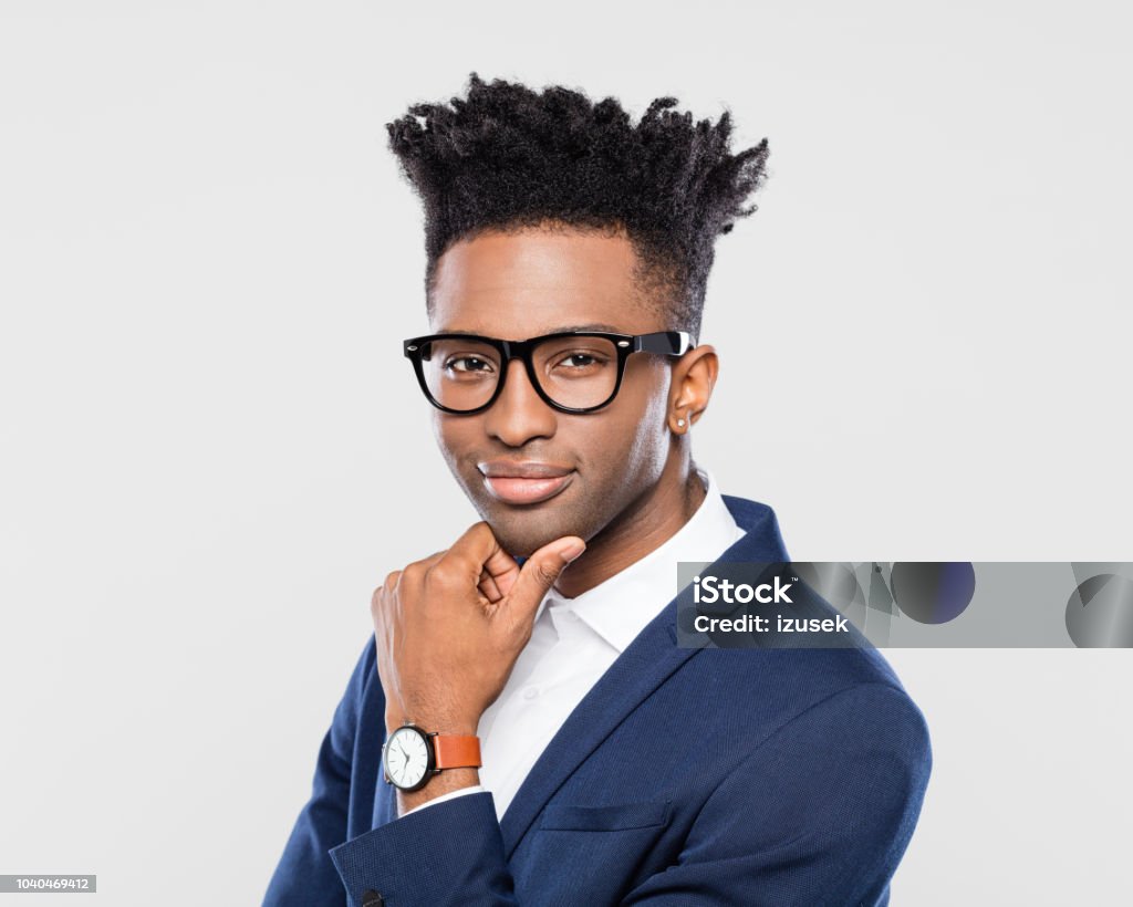 Confident young african businessman Closde up portrait of young afro american businessman standing with his hand on chin on white background. Contemplation Stock Photo